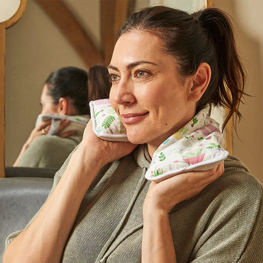 A woman holds the lavender heat pack around the back of her neck