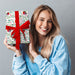 A woman holding a wrapped present. The wrap is white with illustrations of water colour robins amongst leaves and berries.