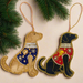 Two fabric Labrador decorations, one yellow with blue embellished jacket and one black with red embellished jacket with hanging loops