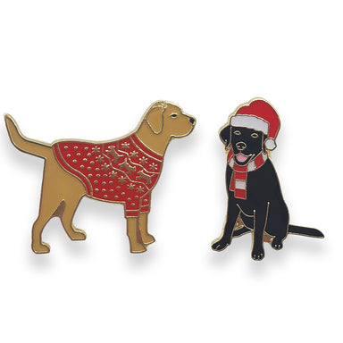 Two pin badges, one featuring a golden Labrador wearing a red Christmas jumper, the other featuring a black Labrador wearing a Santa hat and red and white stripe scarf.