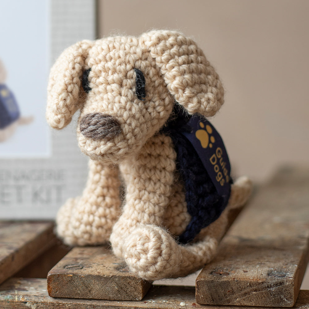 A photograph of a mini crochet Yellow Labrador with a blue Guide Dogs jacket and stitched logo.