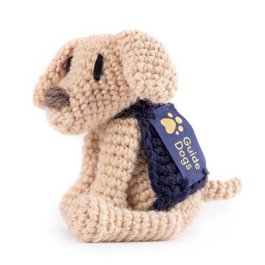 A photograph of a mini crochet Yellow Labrador with a blue Guide Dogs jacket and stitched logo.