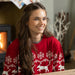 A woman sat on the floor in a living room wearing a red Christmas jumper with white detailing including a repeating pattern of snowflakes and Labradors.