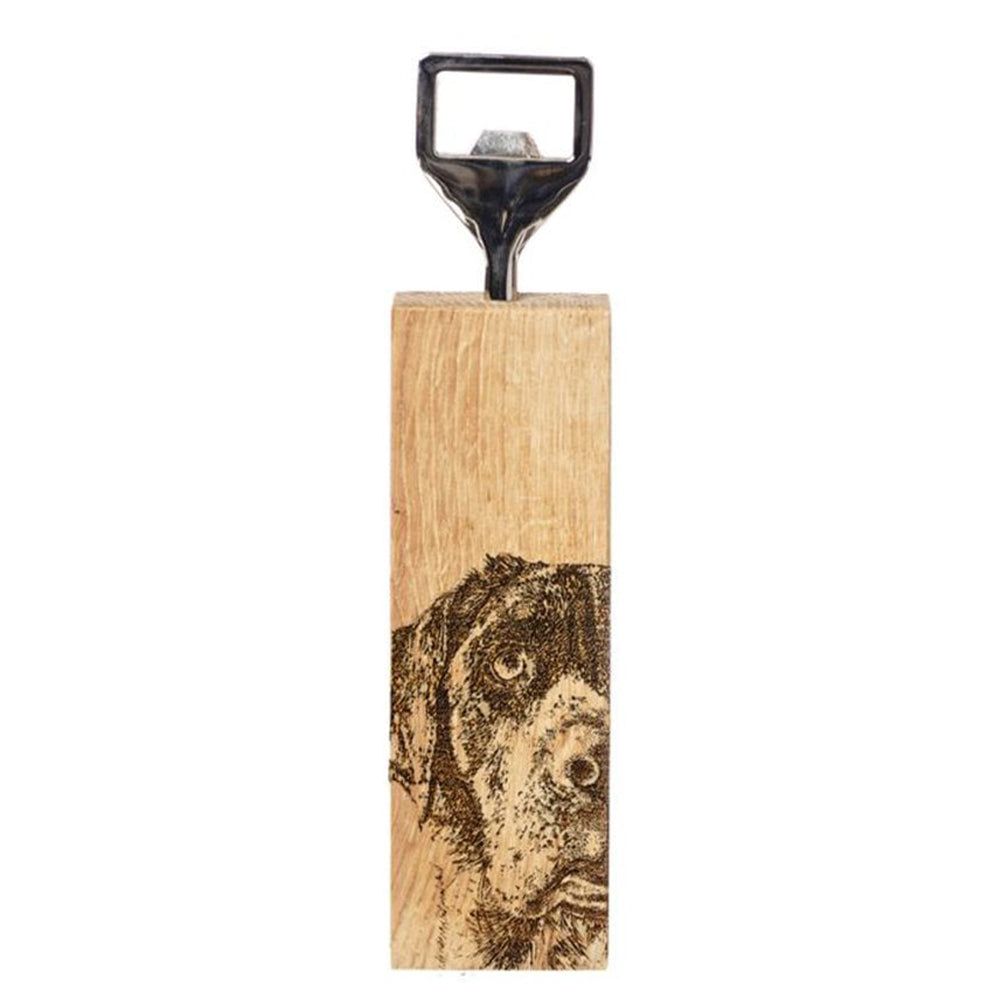 A metal bottle opener with wooden base. The base has an engraved illustration of a Labrador.