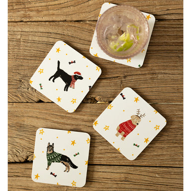 Four coasters on a wooden background. Each coaster features a different festive dog: German Shepherd, Yellow Labrador, Golden Retriever and Black Labrador. The Golden Retriever is covered by a glass.