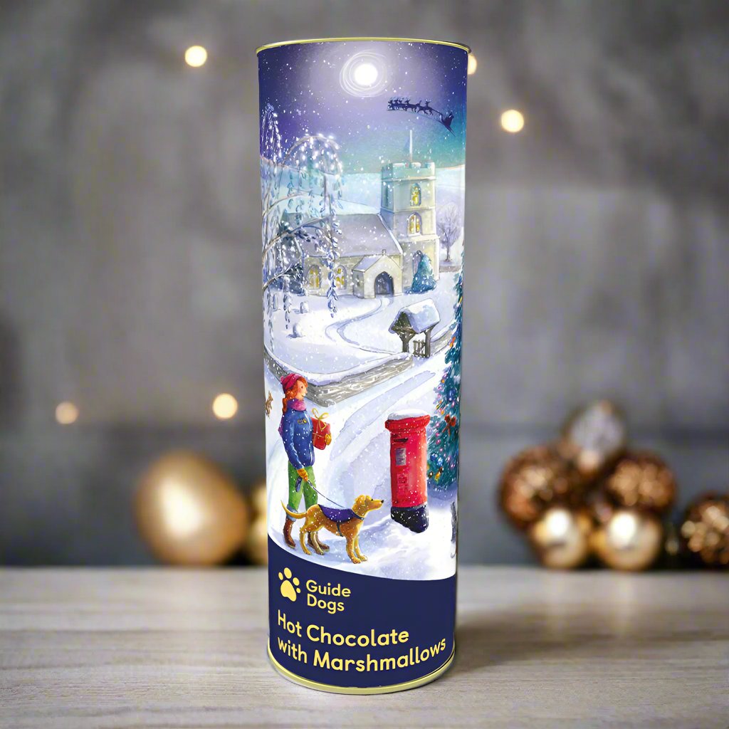 A tall cylinder containing hot chocolate and marshmallows, with a label featuring a Christmas village illustration.