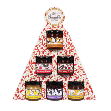 Six mini jars of preserves presented in packaging the shape of a Christmas tree.