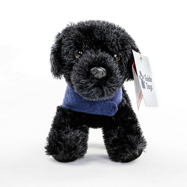 A close up of a Black Labrador cuddly toy with a blue Guide Dogs coat on. Front facing.