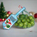 Chocolate sprouts in a green net bag with a blue label, on a table with Christmas decorations in the background.