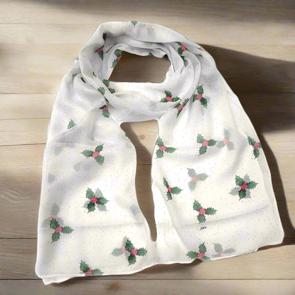 A white looped scarf printed with green holly sprigs and red berries