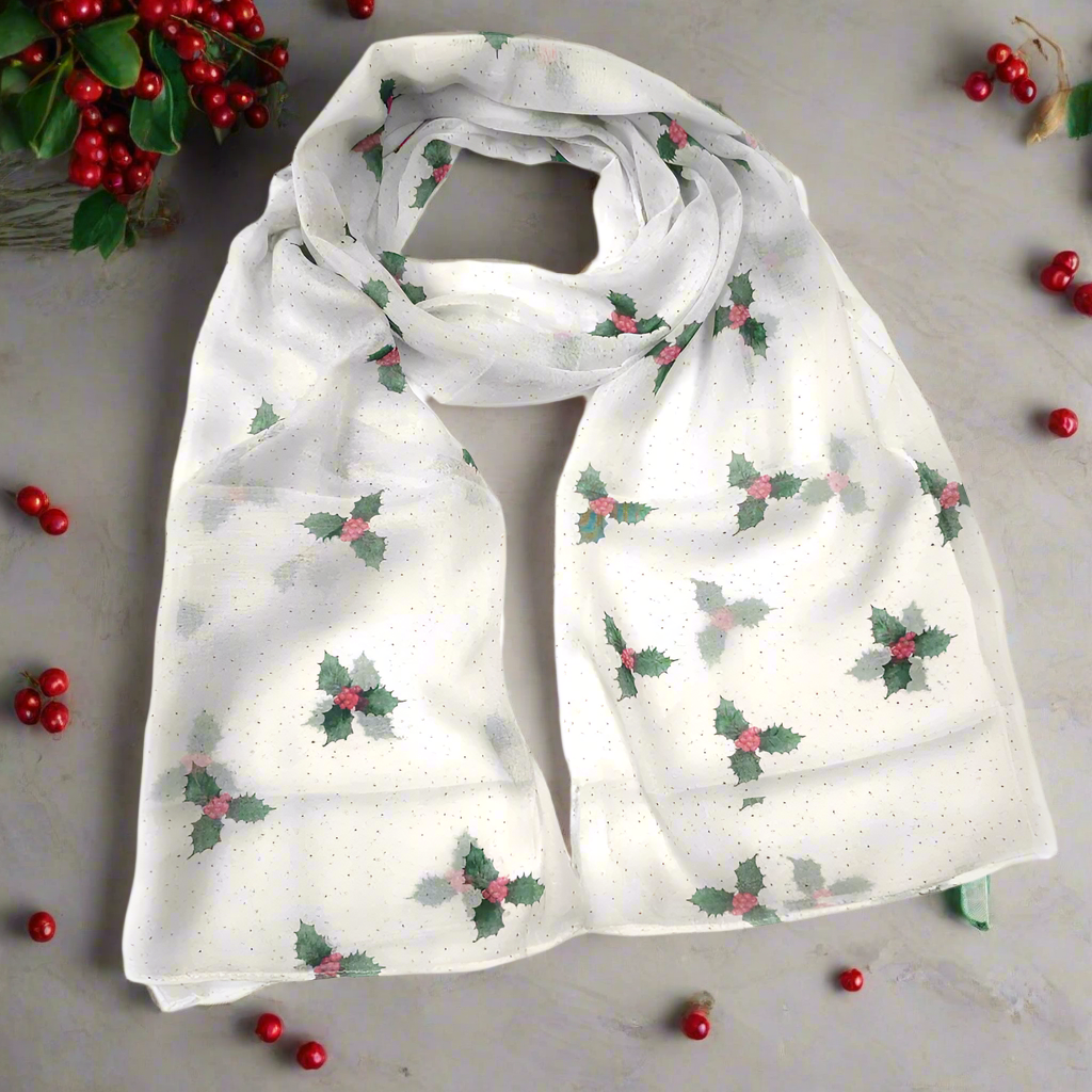 A white looped scarf printed with green holly sprigs and red berries