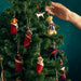 A fir tree is decorated for Christmas and a hand is shown adding a decoration 