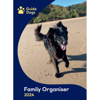 The front cover of the Guide Dogs 2024 A3 Family Organiser. A Labrador Retriever runs across the beach.