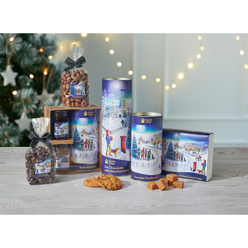 Festive treats featuring an illustration of a village covered in snow, with people posting Christmas cards, singing hymns and making snowmen. This design is exclusive to Guide Dogs.