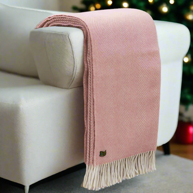 A dusty pink throw hanging off the arm of a sofa. In the background is a Christmas tree.