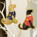 Two fabric Labrador decorations, one yellow with blue embellished jacket and one black with red embellished jacket with hanging loops