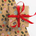 A piece of wrapping paper appears underneath an already wrapped present with red ribbon. The wrap is brown with illustrations of candy canes and festive presents.