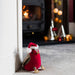 Robin shaped doorstop with red Santa hat is propped up against a door. A fireplace roars in the background.