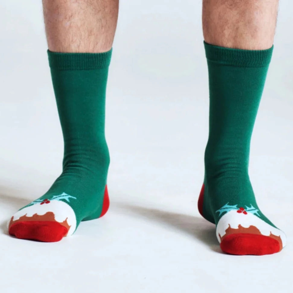 Man's lower legs wearing green socks with Christmas pudding toes