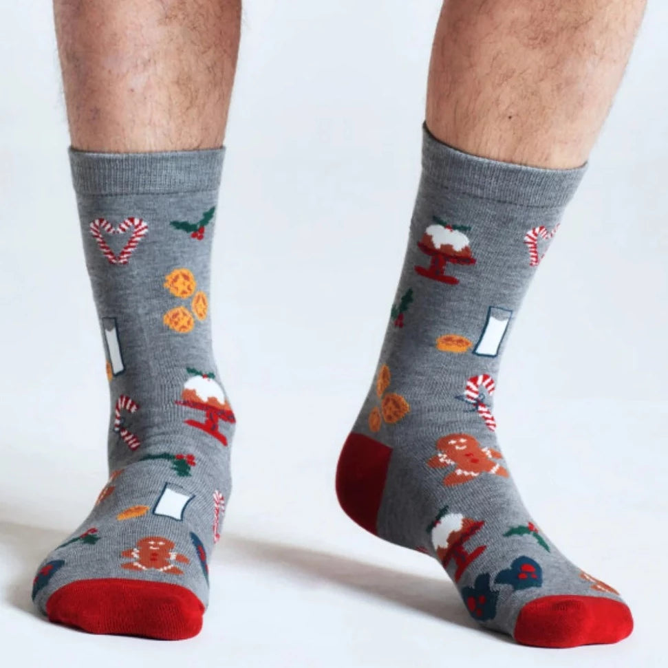 Man's lower legs wearing grey socks with Christmas pattern including holly and gingerbread men