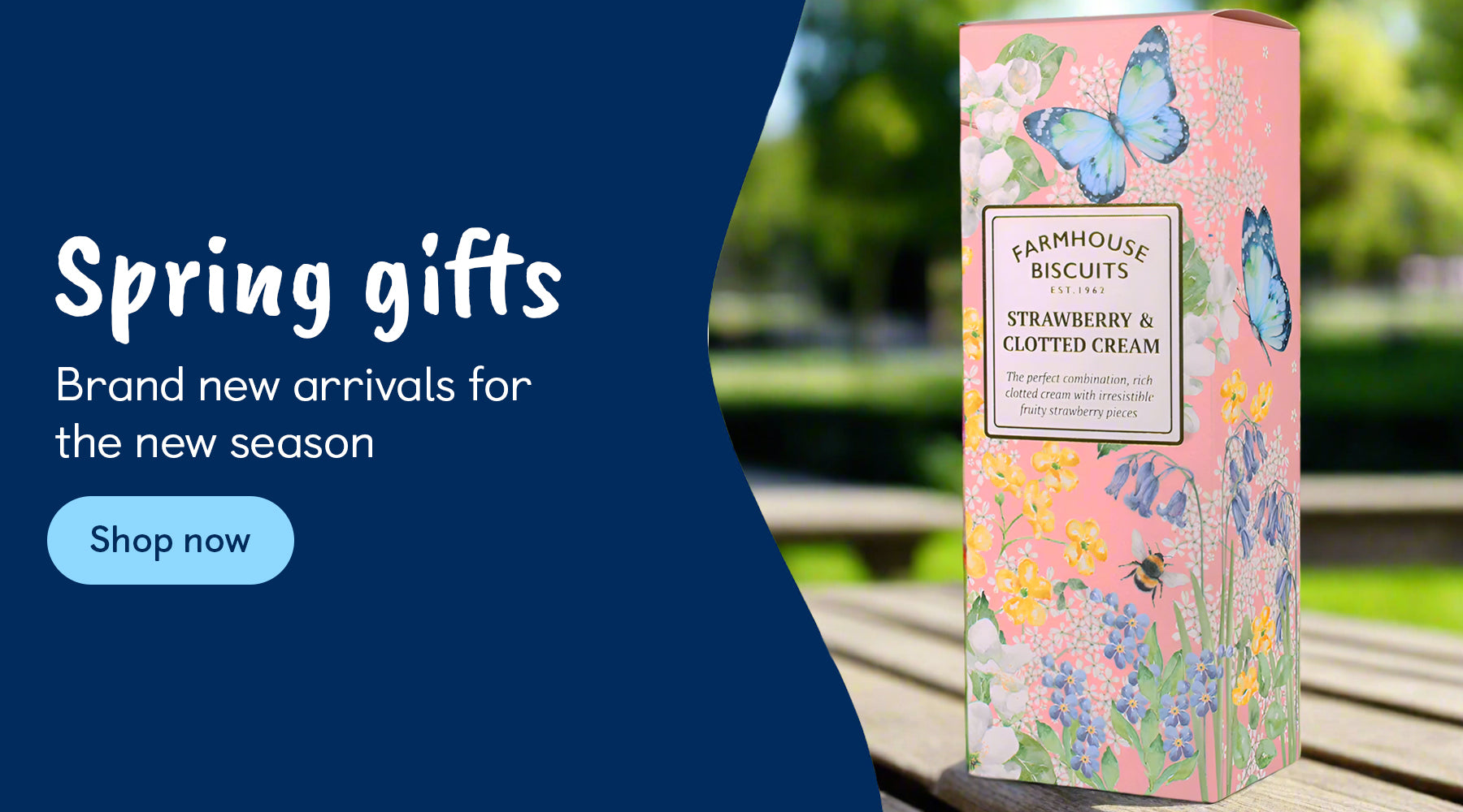 A pink box on a park bench that features illustrations of flowers, butterflies and bees. The box contains strawberry and clotted cream farmhouse biscuits. There is an ask to shop via the Spring Gifts category.