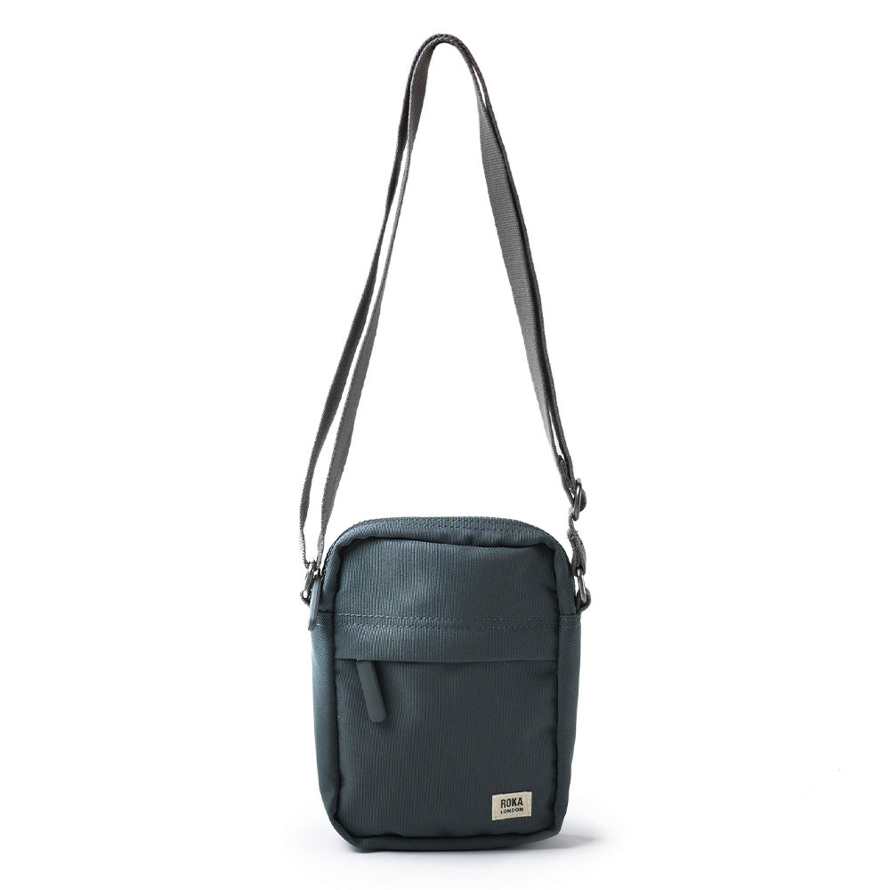 A photograph of a grey rectangular bag featuring a zipped front pocket and ROKA logo.