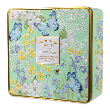 A close up of the mint green tin containing honey and oat farmhouse biscuits. The tin has gold detailing and features flowers, butterflies and a bee.