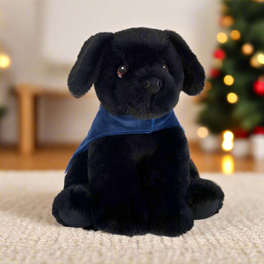 A black Labrador soft toy wearing a blue Guide Dogs coat