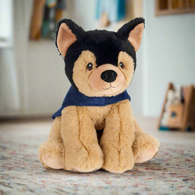 A German shepherd soft toy wearing  a blue Guide Dogs coat.