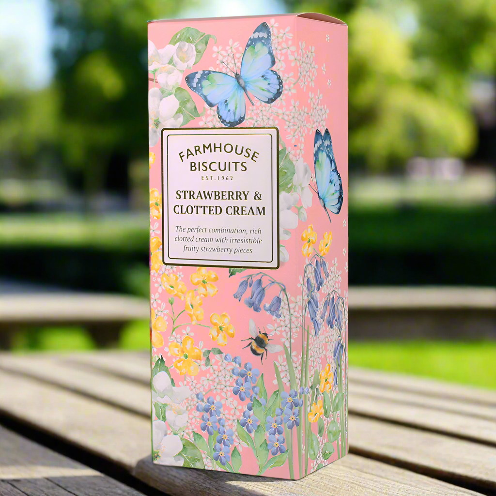 A pink box on a park bench that features illustrations of flowers, butterflies and bees. The box contains strawberry and clotted cream farmhouse biscuits.