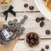 Seen from above, a close up of a white wooden table with dark chocolate pieces in a small bowl next to a package with the Guide Dogs label on it