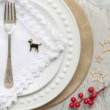 Christmas table setting with black Labrador Christmas badge on a white napkin next to a fork