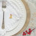 Christmas table setting with golden Labrador pin badge on top of a white napkin next to a fork