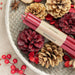 A bundle of dark red candles sits in a basket of pine cones 