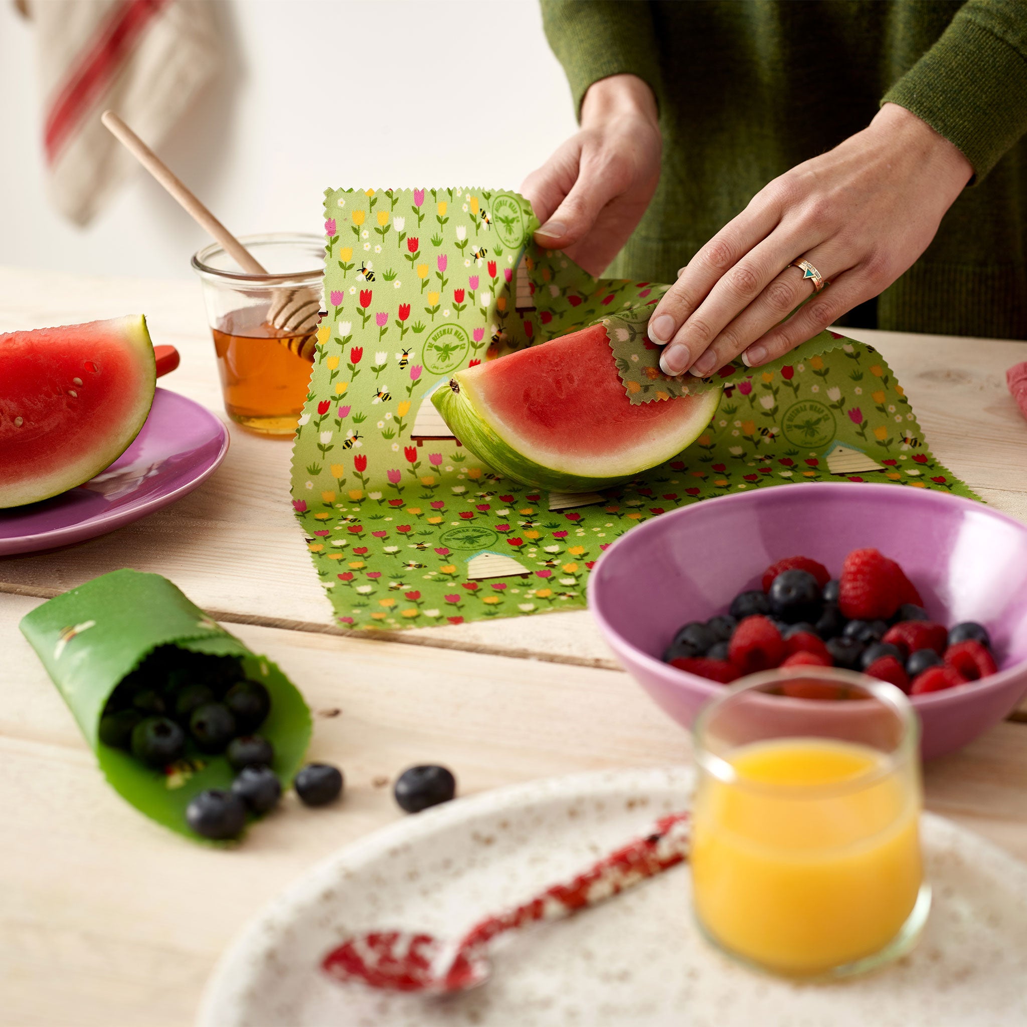 Lifestyle image of a woman wrapping a piece of watermelon up in a Beeswax wrap.