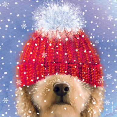 The design is illustrated and golden dog with a red bobble hat pulled down over their eyes. On a blue background with white snowflakes.