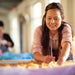 Images shows fairtrade crafts people in Nepal making decorations, a woman lays out felt on a table.