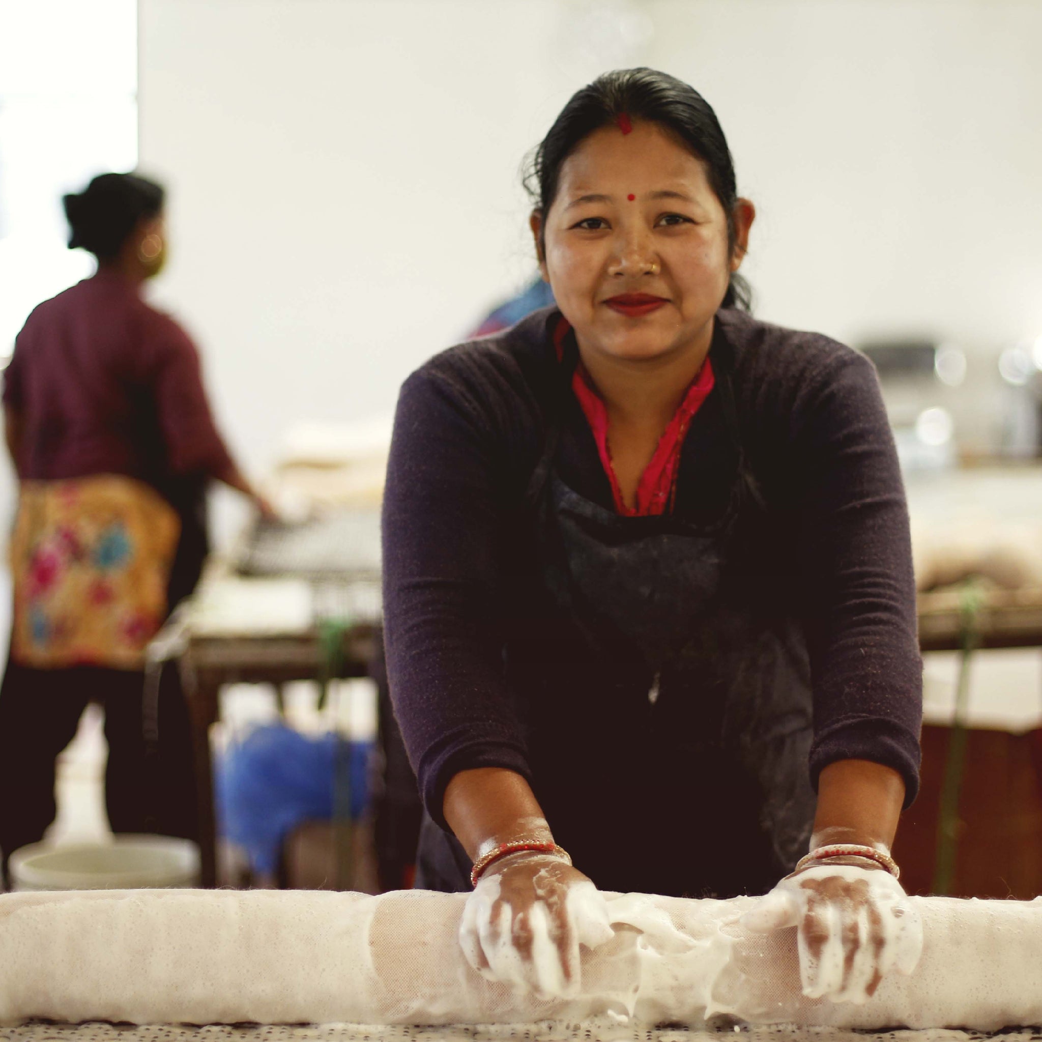 A Fairtrade craftswoman is rolling felt with soap to create fabric.