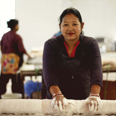 A Fairtrade craftswoman is rolling felt with soap to make fabric.