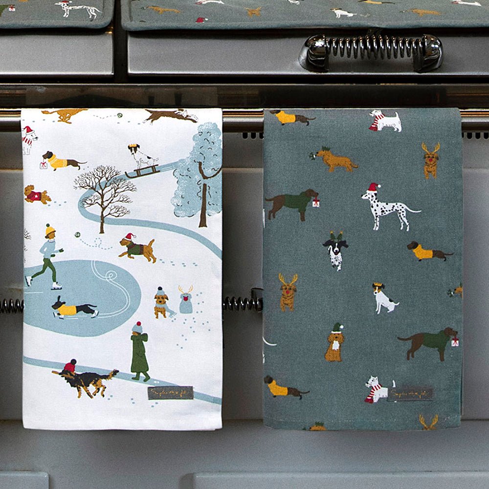 Two Christmas tea towels hanging from a range cooker.