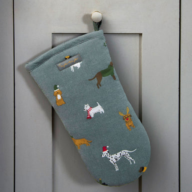 A Christmas design oven mitt hanging from a cupboard door.