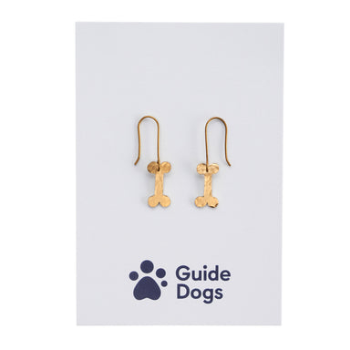 Brass earrings with a dog bone decoration on Guide Dogs branded packaging.