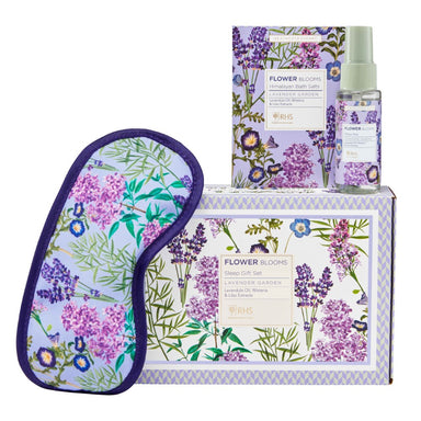 Floral eye mask leans against a lavender floral gift box, on top of which sit a sachet of bath salts and pillow spray bottle