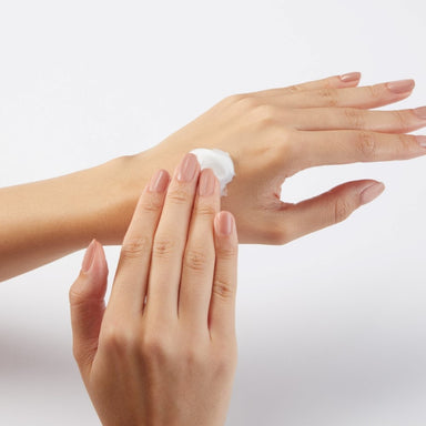 A pair of woman's hands, one hand is rubbing cream into the other