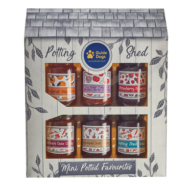 A close up of the Potting Shed, a gift box of both sweet and savory preserves in a a box decorated to look like a shed. The Guide Dogs logo is at the top and the box reads "Mini Potted Favourites".