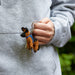 A black and brown crocheted German Shepherd keyring being held in a person's hand.