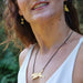 A lady with brown wavy hair wears brass jewelry. Around her neck is the leaping dog brass necklace. In her right ear she is wearing the brass bone earrings, in the left ear a dog shaped earring.