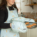 model using laura fisher double oven gloves with puppy design holding tray of baked treats