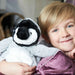 Smiling boy with blond hair holds soft toy penguin