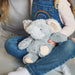 Child in dungarees holds soft toy elephant in her lap
